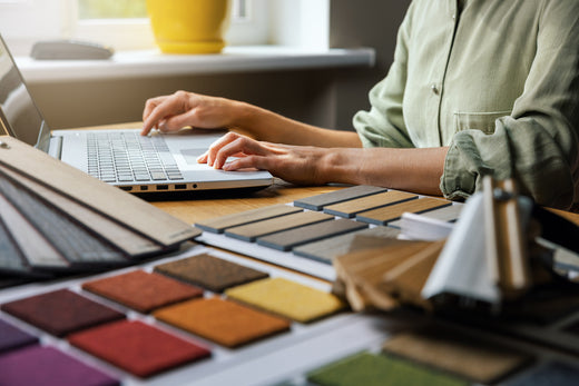 Woman searching on laptop for tiles while surrounded by tile samples